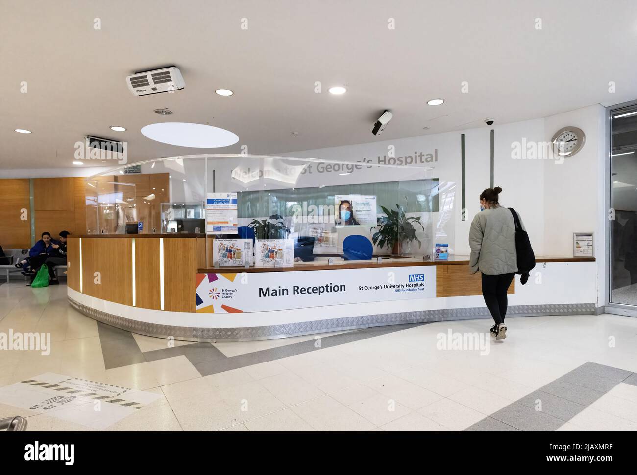 Hospital reception UK; main reception desk, and patient; interior, St Georges Hospital, Tooting, London UK. A large London NHS Teaching Hospital Stock Photo