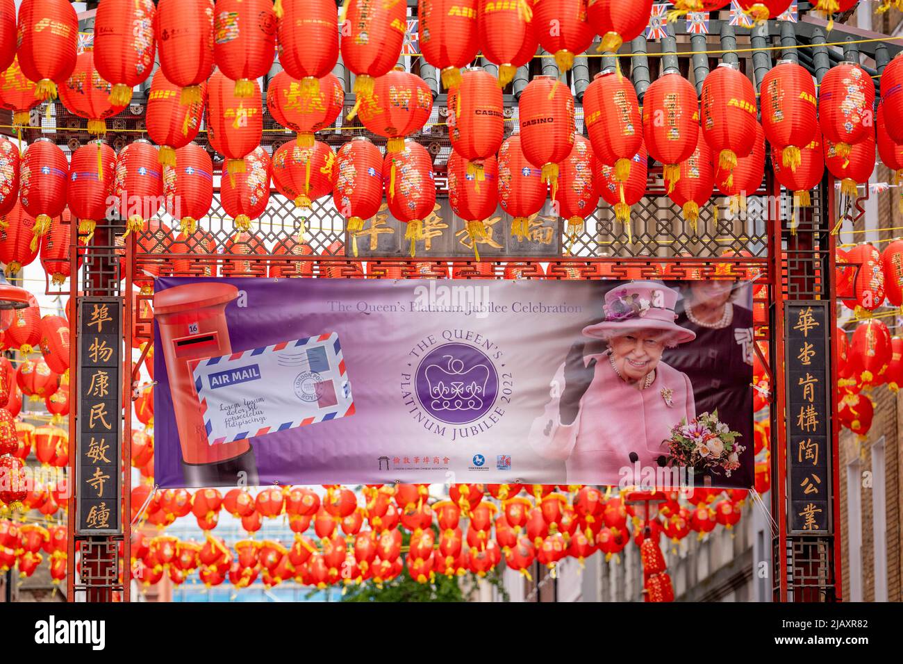 Days before the Queen's Platinum Jubilee celebrations commence over the Bank Holiday acros the UK, a banner showing her face hangs among Chinese lanterns on Garrard Street in the heart of the capital's Chinatown, on 1st June 2022 in London, England. Queen Elizabeth II has been on the UK throne for 70 years, the longest-serving monarch in English history and Union Jack flags can be seen everywhere around the country in the week before the Jubilee weekend. Stock Photo