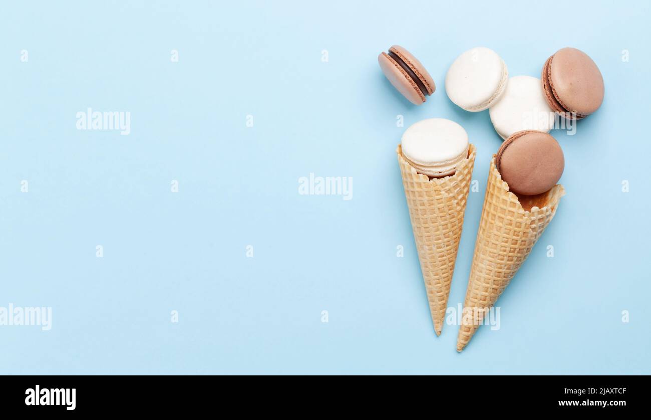 Various macaroon cookies in ice cream cones. Flat lay on blue ...
