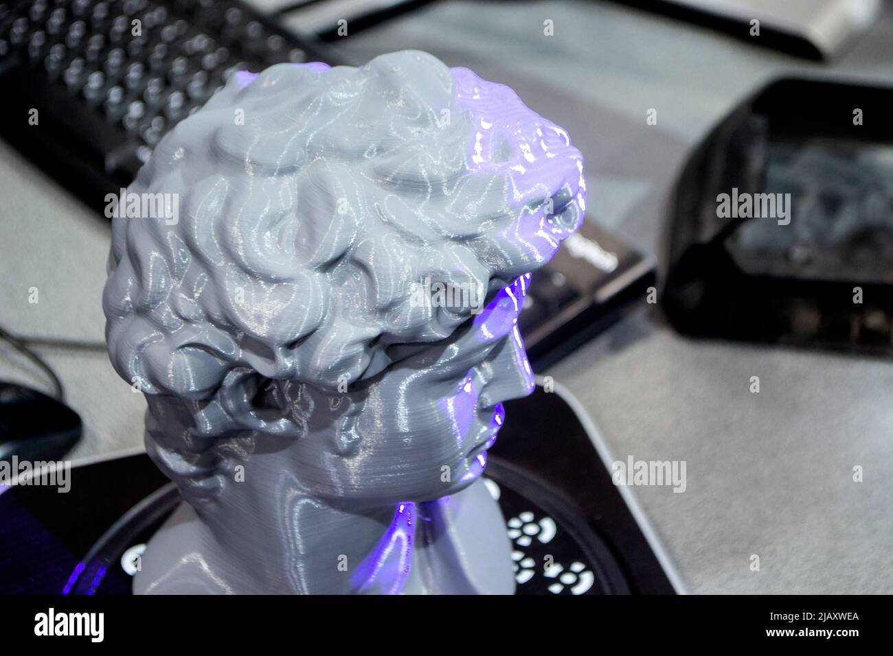 Gray human head on 3d printed close-up. An object prototype of a human head with hair printed by a 3D printer stands on a table. New modern additive 3D printing technology. Fused deposition modeling Stock Photo