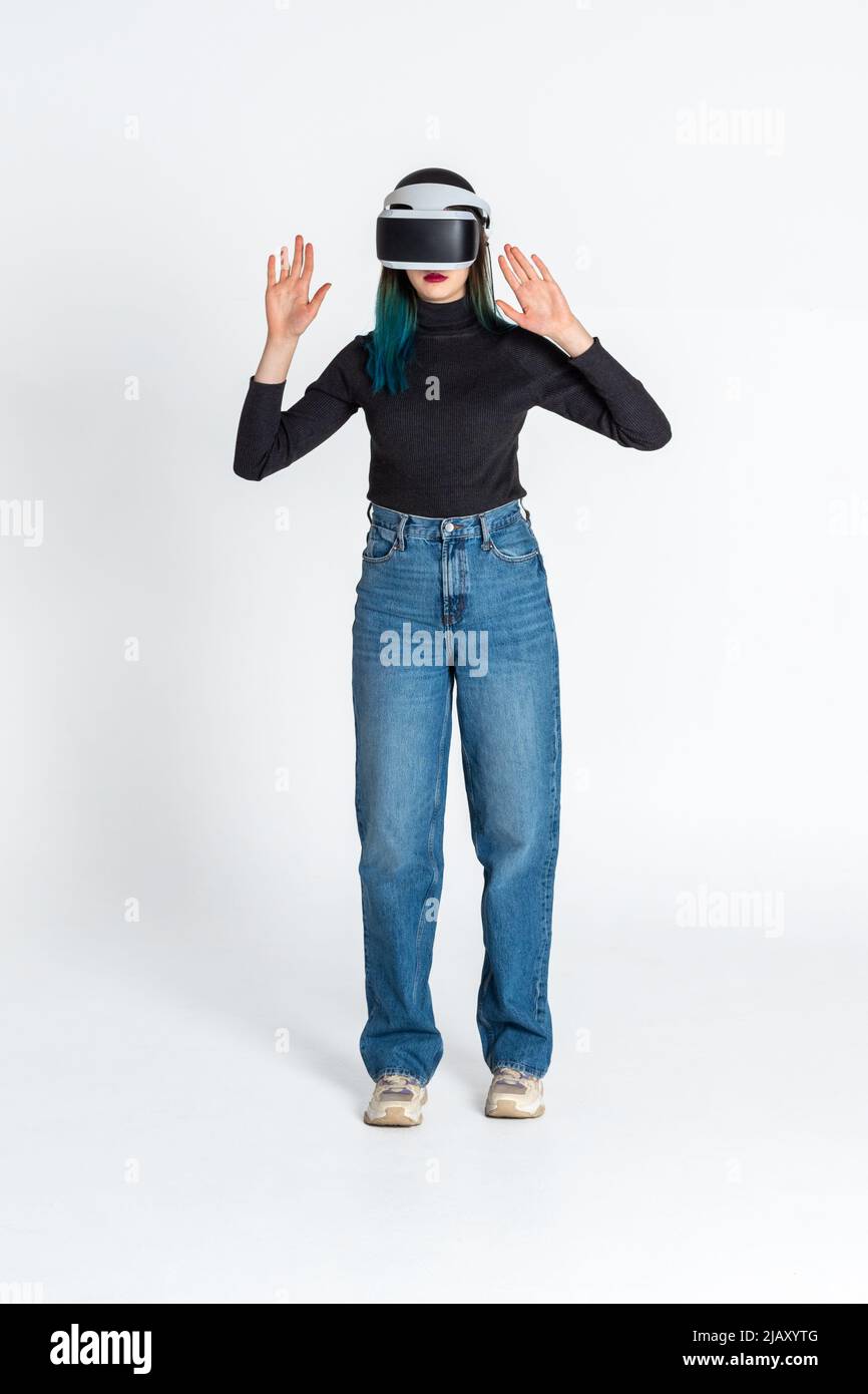 Teen girl using vr headset is in virtual reality cyberspace futuristic white background. The concept of the metaverse, virtual reality, virtual social Stock Photo
