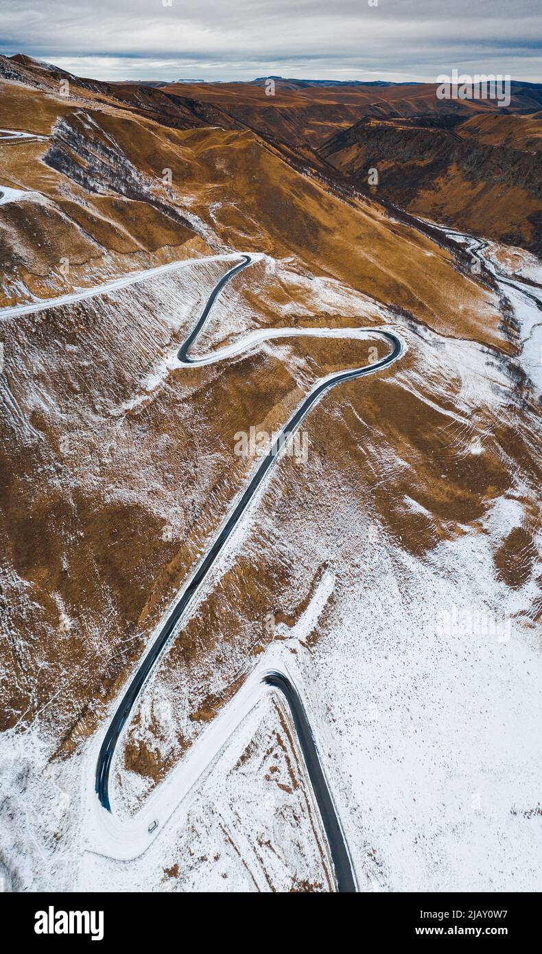 mountain serpentine on the slope of a snowy mountain view from a drone Stock Photo