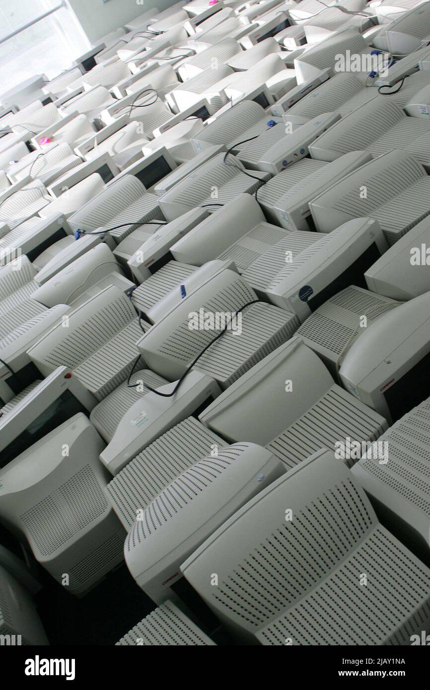 Old computer monitors stored in modern office area awaiting recycling