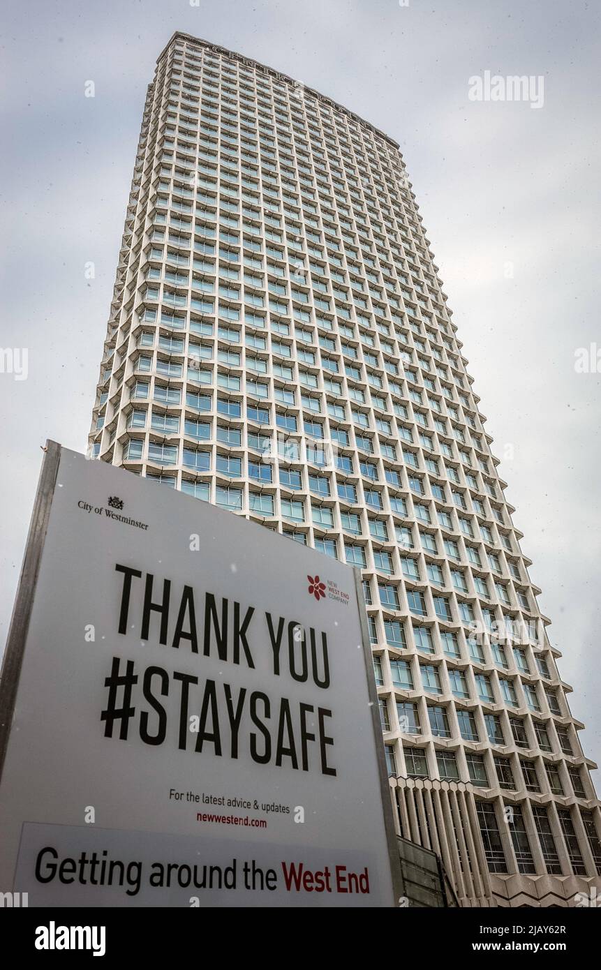 Covid 'Stay safe' sign with Centrepoint building in the background outside Tottenham Court Road tube station, central London. Stock Photo