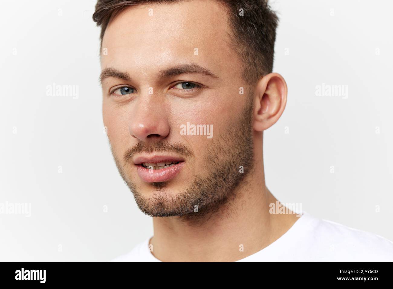 Closeup portrait. Flirted tanned handsome man in basic t-shirt raises ...