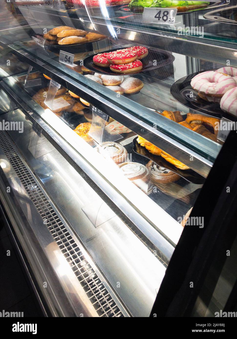 cakes and donuts at sale in cafe refrigerated bakery case Stock Photo