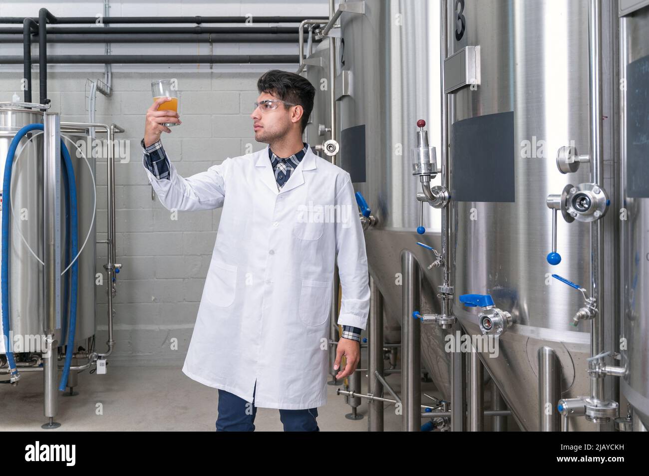 Brewer wearing white coat controlling process of beer fermentation