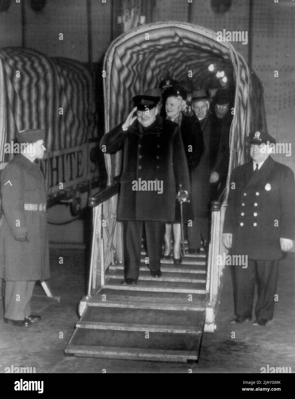 Churchill Arrive Aboard Queen Elizabeth : Winston Churchill, former British Prime Minister, salutes with a smile as he steps from a Gangplank after arriving here today Aboard The Liner Queen Elizabeth. Behind him is Mrs. Churchill. January 12, 1946. (Photo by AP Wirephoto). Stock Photo