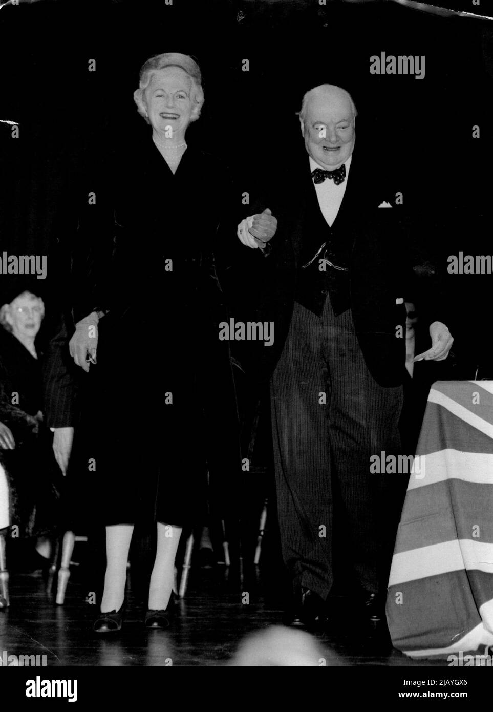 Sir Winston Gives A Come-And-Look Lead: Sir Winston Churchill takes his wife by the wrist and smilingly leads her to a portrait of Lady Churchill which was presented to the Prime Minister this evening (Tuesday) at a meeting of his constituents in the Girls County High School, Woodford, Essex. The portrait was presented to Sir Winston to mark his 80th birthday, on November 30. November 23, 1954. (Photo by Reuterphoto). Stock Photo