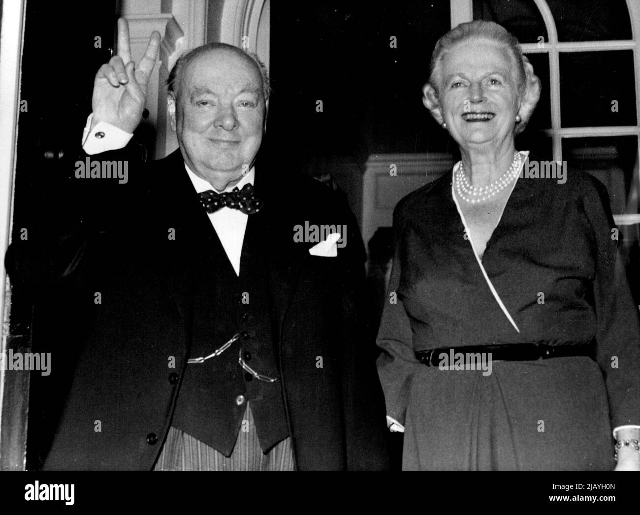 Sir Winston Churchill, celebrating his 81st birthday Anniversary today November 30, makes the 'V' sign as he poses with his life at the door of their London residence at Hyde Park Gate. November 30, 1955. (Photo by Associated Press Photo). Stock Photo