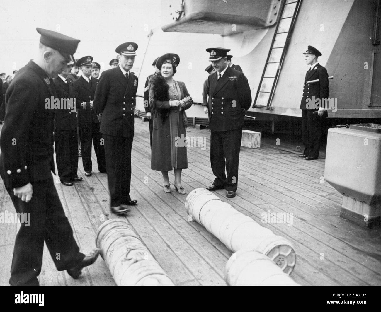Royal Visit to Famous British Battleship - The King and Queen with the Commanding Officer of the King George V - Captain T. E. Halsey, D.S.O., R.N., watching 14-inch cordite charges being rolled across the deck. Picture taken at a Northern Base when the King and Queen accompanied by Princess Elizabeth and Princess Margaret, paid a farewell visit to he British Battle-ship King George V before she left to join Britain's East Indies Fleet. It is now revealed that the King George V took part in tie great air-sea operations against Japanese oil supplies in Sumatra. April 16, 1945. (Photo by PNA). Stock Photo