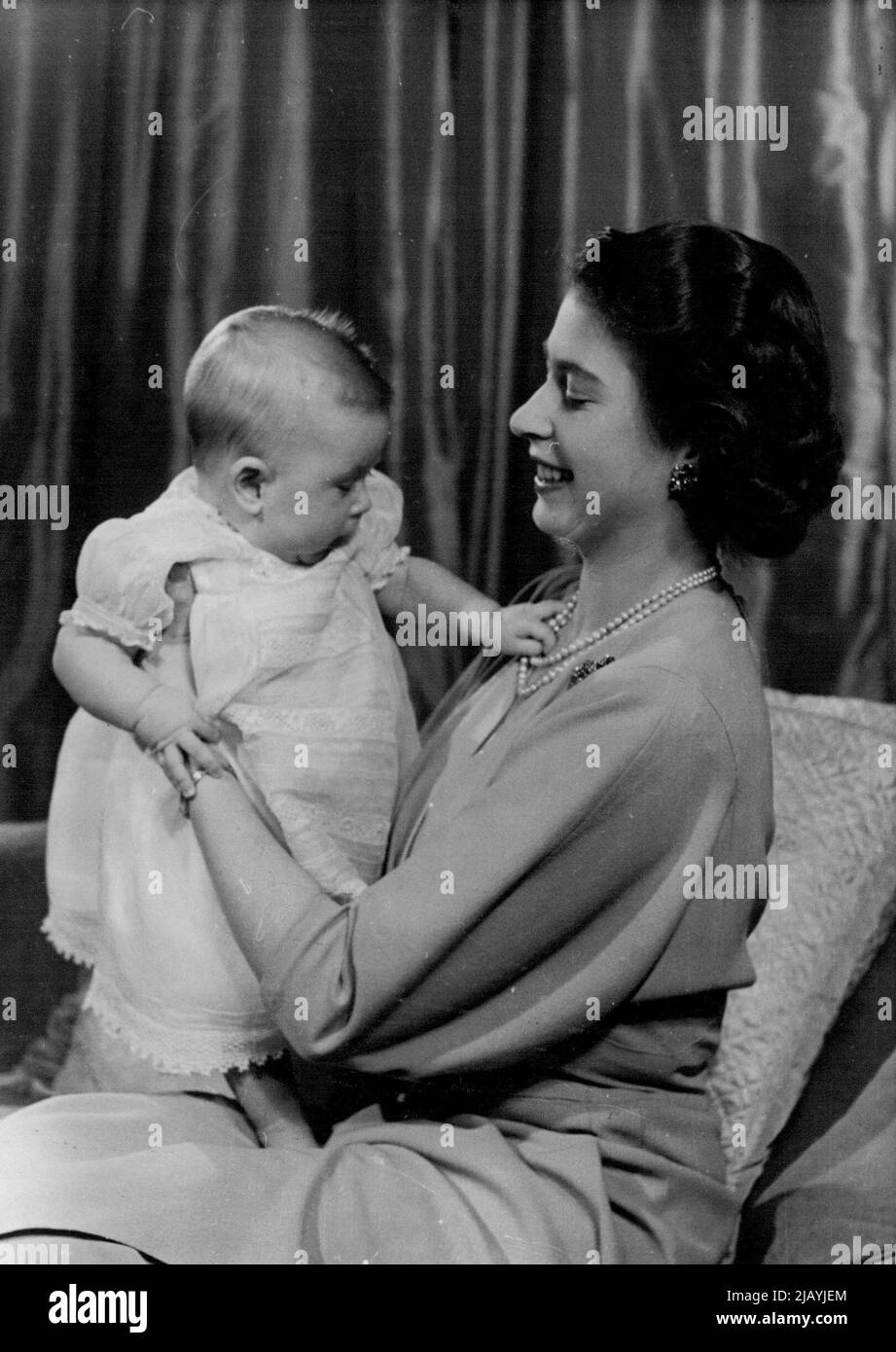H.R.H. Princess Elizabeth And Prince Charles : First informal photograph of H.R.H. Princess Elizabeth at play with her infant son. The picture was taken in Princess Elizabeth's private sitting room at Buckingham Palace. Her Royal Highness is dressed in dove-grey. April 9, 1949. (Photo by Baron, Camera Press). Stock Photo
