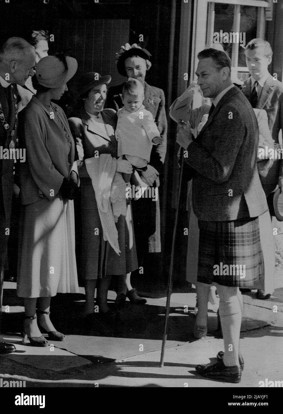 Bonnie Prince Charles Crosses The Border -- Prince Charles makes a grab for his grandfather's stick as his Nurse, Helen Lightbody carries him from Ballater Station. At left is Princess Elizabeth, next to canon W.E. Adams (extreme left) provost of Ballater. (Queen Elizabeth is hidden by the King, others unidentified). Young Prince Charles made a raid across the border between England and Scotland August 6, and captured the hearts of the highlanders who saw him for the first time since his birth nearly a year ago. With his mother, Princess Elizabeth, aunt Princess Margaret and grandparents, King Stock Photo