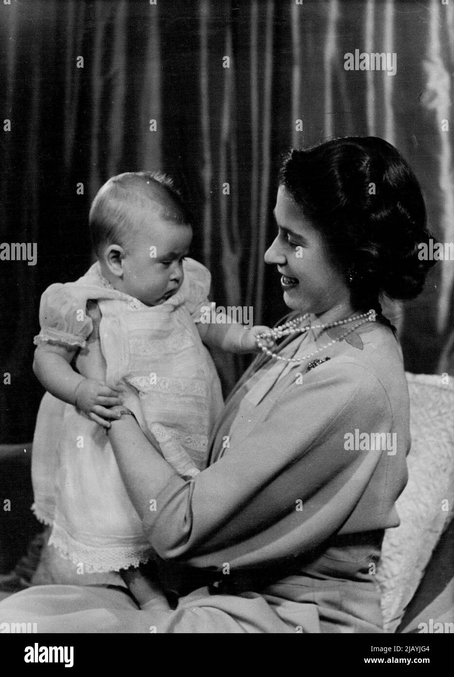 H.R.H. Princess Elizabeth And Prince Charles : First informal photograph of H.R.H. Princess Elizabeth at play with her infant son. The picture was taken in Princess Elizabeth's private sitting room at Buckingham Palace. Her Royal Highness is dressed in dove-grey. April 9, 1949. (Photo by Baron, Camera Press). Stock Photo