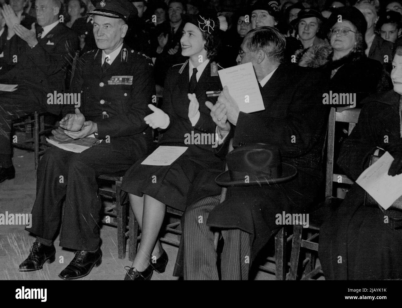 Princess Sees St. John Ambulance Competitions -- Princess Margaret, wearing the uniform of Commandant-in-Chief of the St.John Ambulance and Nursing Cadets, applauding one of the teams of Cadets then they competed for trophies it the Finals of the National First Aid and Home Nursing Competitions at the Central Hall, Westminster here. Forty-three teams from twenty-two English counties, Wales and Northern Ireland, competed for the challenge shields, cups and various prizes which were presented by the Princess. On left is Lieut-General Sir Henry Pownall, Chief Commissioner of the force. November 6 Stock Photo