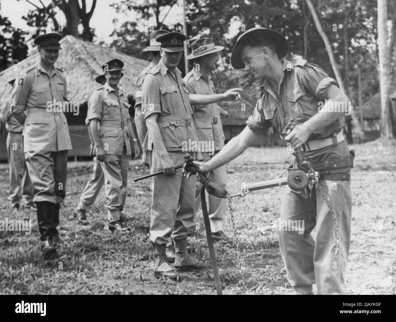 Sig. L. Angel (Wagga, NSW) at work on a signal line wire strainer. The Duke of Gloucester looks on. Release Monday afternoon. July 06, 1945. Stock Photo