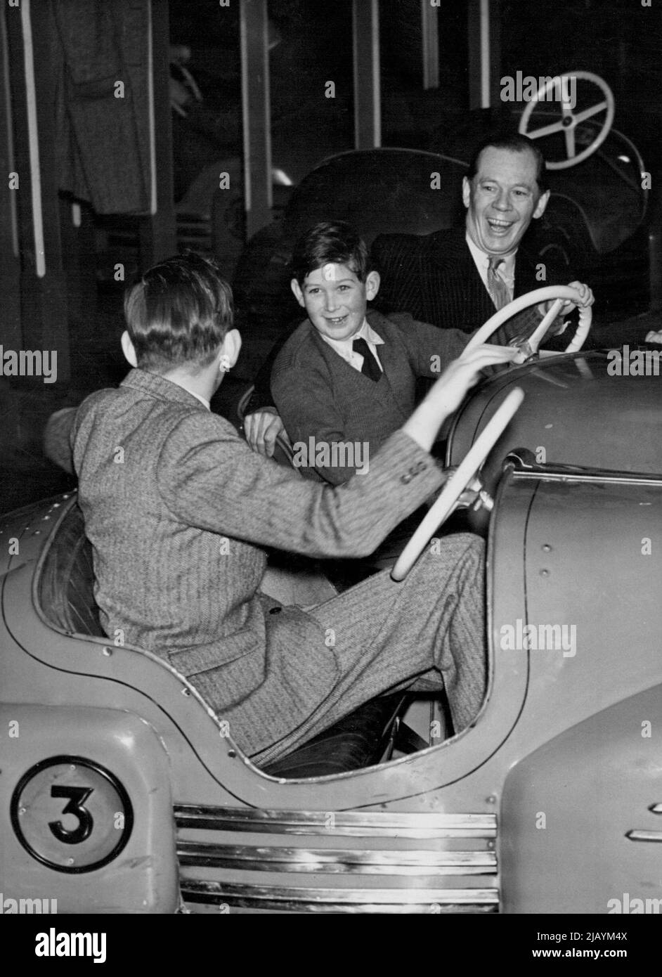 Royal Children Visit Circus And Fun Fair -- 'Dodgem with the Duke' A back view of the Duke of Kent as he bumps his brother Prince Michael who rides with Mr. Cyril Mills at the Fun Fair today. The Duchess of Kent's two children the young Duke of Kent and Prince Michael today visited Bertram Mills Circus at Olympia. Prince Michael of Kent rides the dodgins with his elder brother (back to camera) at the circus. January 10, 1951. (Photo by Fox Photos) Stock Photo