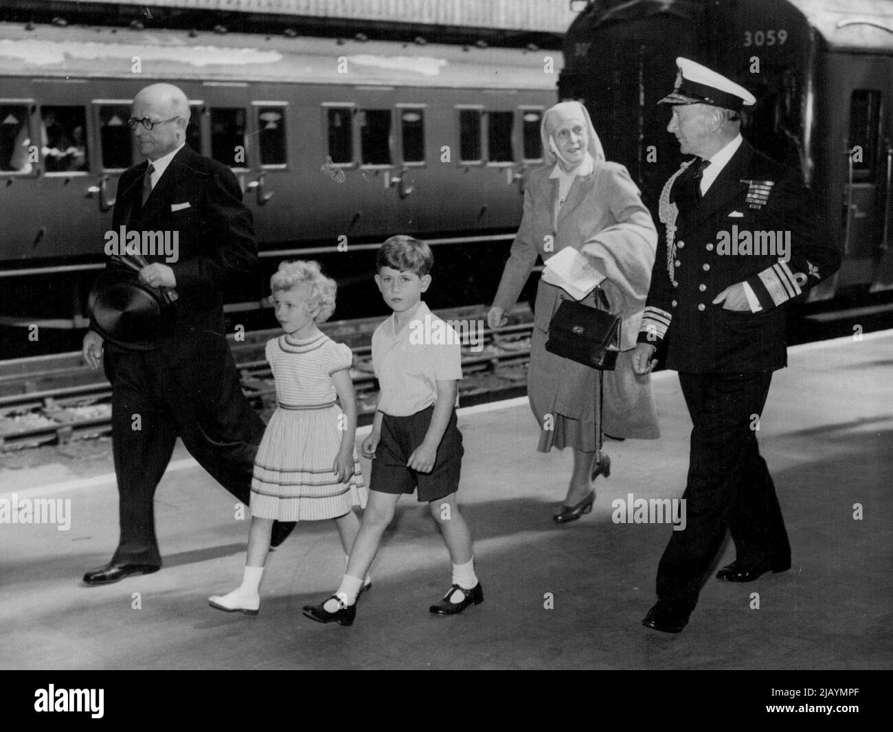 Royal Children Arrive At Portsmouth -- Prince Charles and his sister, Prince Anne, followed by their grandmother, Princess Andrew of Greece, and accompanied by Vice-Admiral Conolly Abel Smith, Flag officer Royal Yachts, and Stationmaster Mr. T. Fryer, walk from the train on arrival at Portsmouth to-day (Friday) from London to embark in the Royal yacht Britannia. They are to join their parents, the Queen and Duke of Edinburgh, on an eight-day cruise, during which the Royal couple will fulfill engagements in Wales, the Isle of Man, and Scotland. August 05, 1955. Stock Photo
