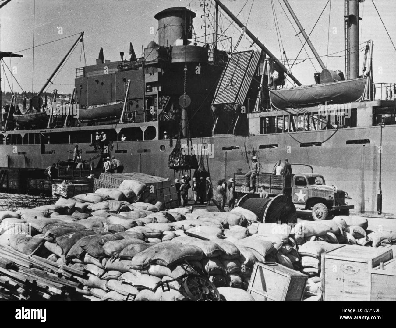 Allied Lend-Lease Supplies Arrive In North Africa -- U.S. Army trucks are loaded with lend-lease supplies on a North African dock piled high with machinery, foodstuffs and other materials which have just arrived from the U.S. on the ship in the background. The cargo was sent to Africa as part of the Allied rehabilitation program for liberated countries. November 06, 1943. (Photo by U.S. Office Of War Information Picture). Stock Photo