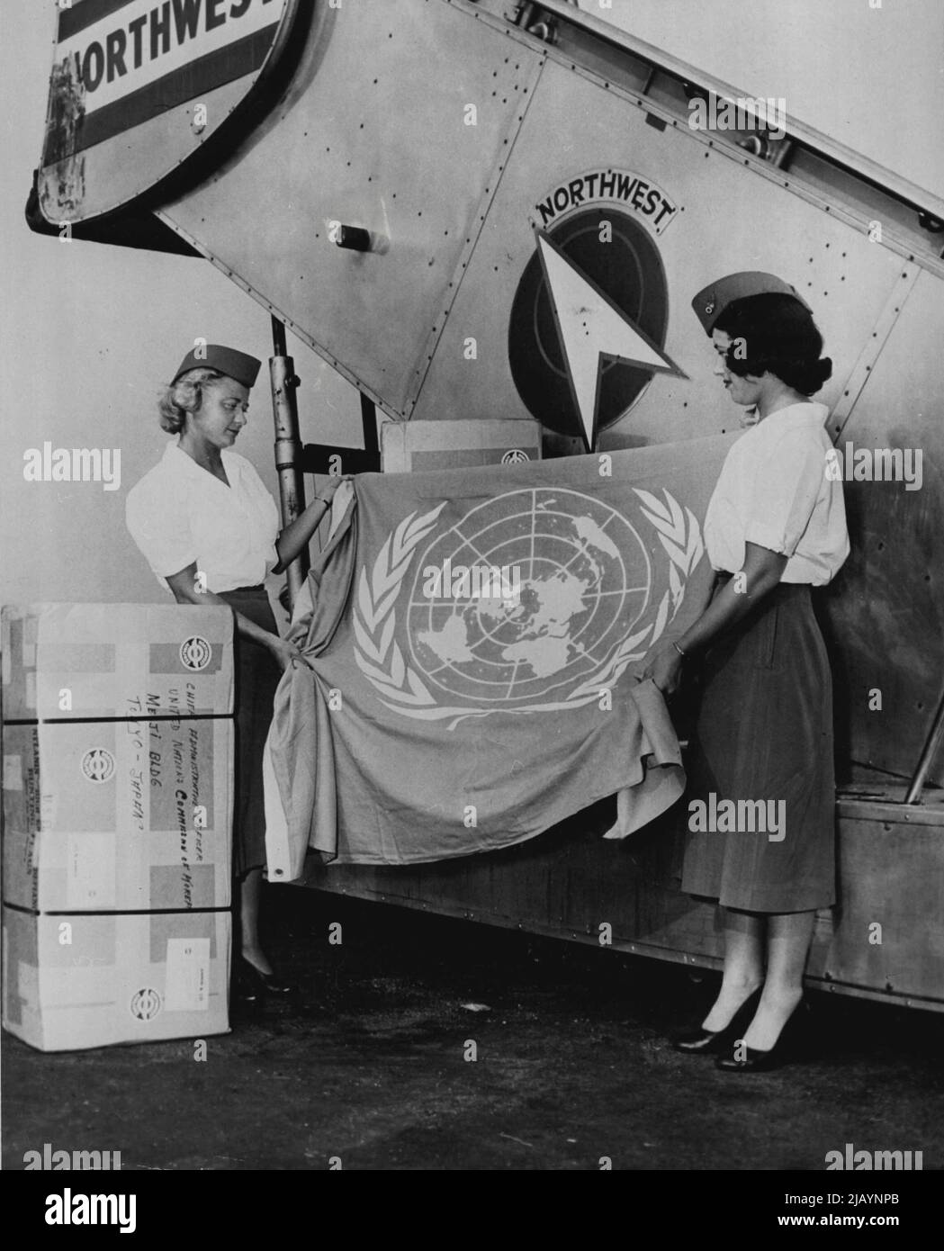 Shipments of blue and white United Nations flags are being made to the unified United Nations forces assisting the Republic of Korea in defense against the North Korean Communist invaders. The use of the UN flag was authorized recently by the UN Security Council. The photograph shows two U.S. airline hostesses holding one of the flags, which are being sent to General of the Army Douglas MacArthur, Commanding General for the unified United Nations forces, to be distributed to the Korean battlefronts. June 21, 1950. (Photo by United States Information Service). Stock Photo