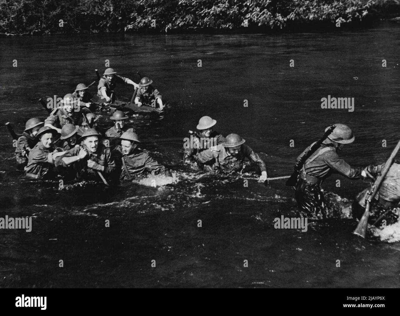 Southern Command Battle Training: Manhandling Anti-Tank Guns Through A River -- Hauling one of the guns out into the river, two crews being needed to handle one gun. A bridge has been blown up but anti-tank guns must get across the river. In sprit of a fast current, the heavy guns, sometimes completely submerged were safely man-handled through the river and went into action on the opposite bank. August 23, 1942. (Photo by British Official Photograph). Stock Photo