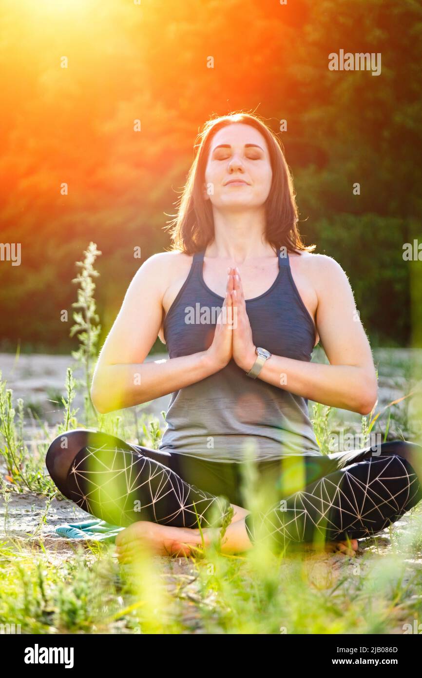 a woman practices yoga and meditates in the lotus position on the sand ...