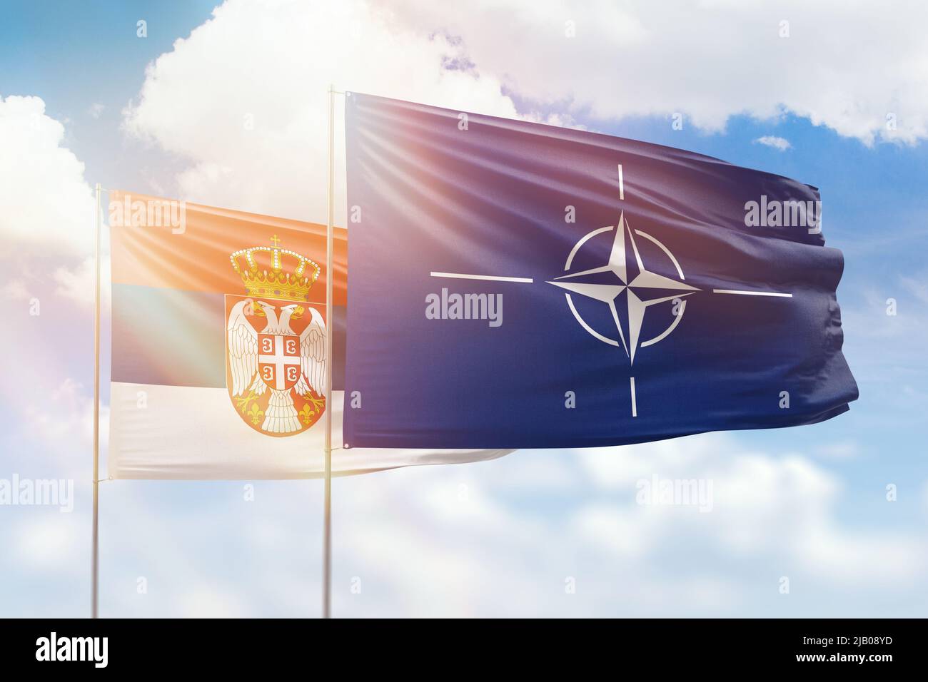 Sunny blue sky and flags of nato and serbia Stock Photo