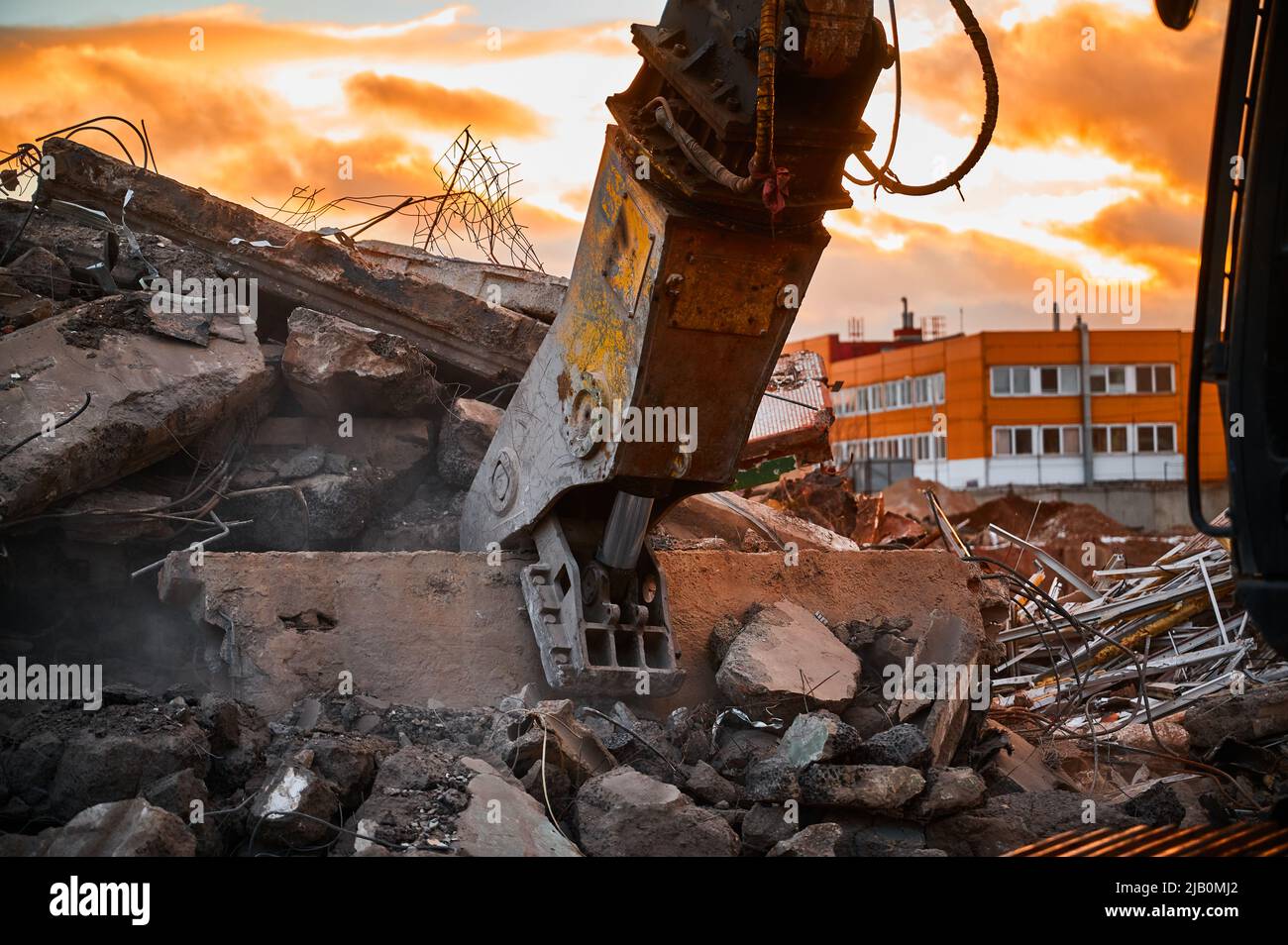 Modern crusher on excavator rigging dismantles concrete beam Stock