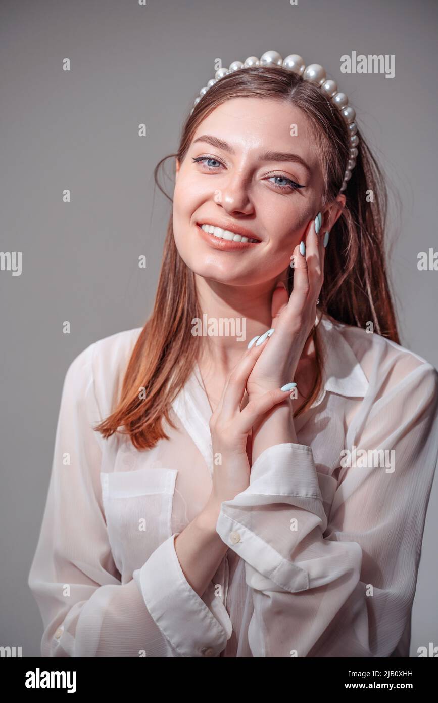 Stylish young woman in white casuals looking away and smiling. vertical Stock Photo