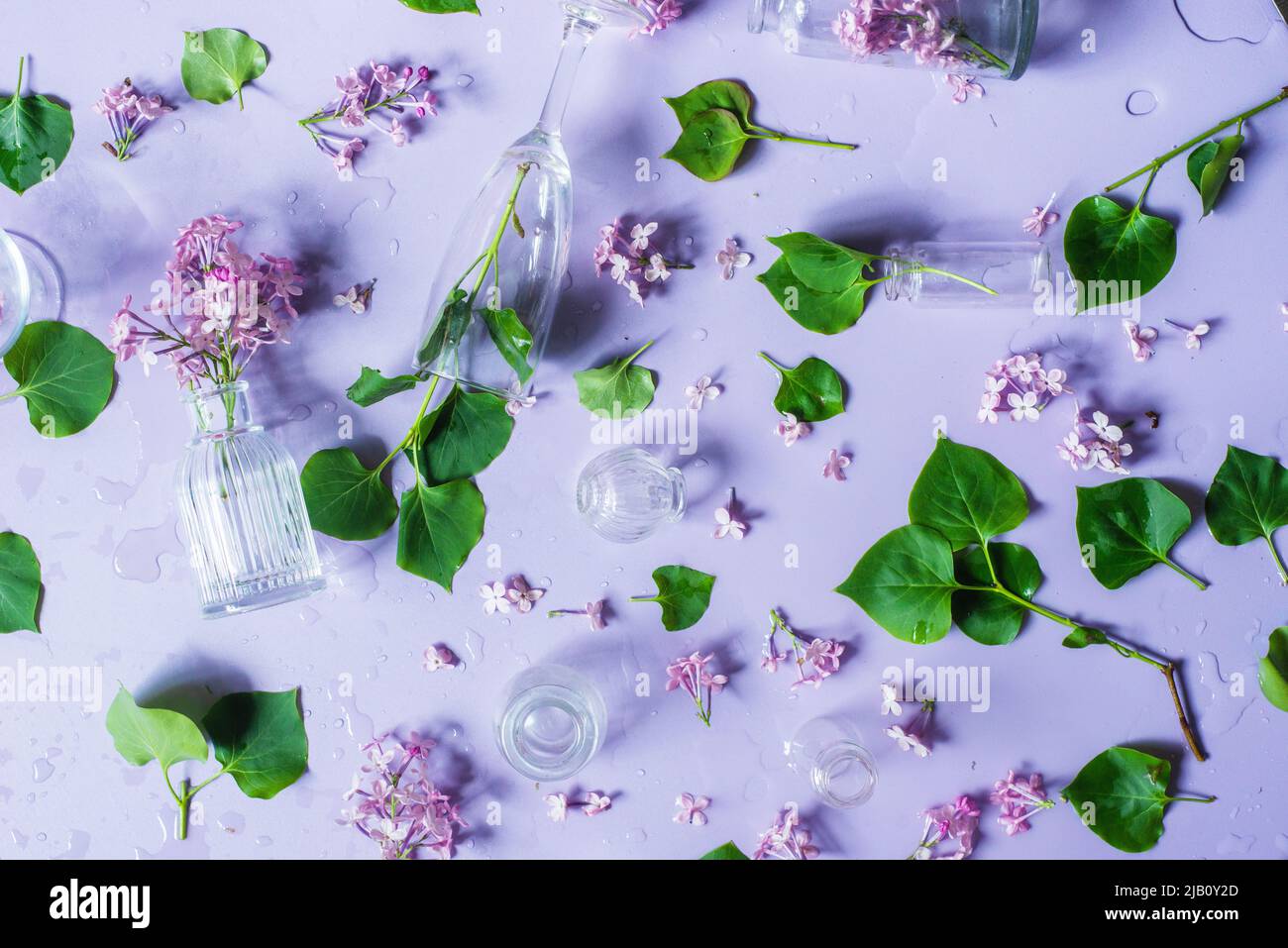 Glass bottles with lilac flowers, pastel colors flat lay, violet still life from above Stock Photo