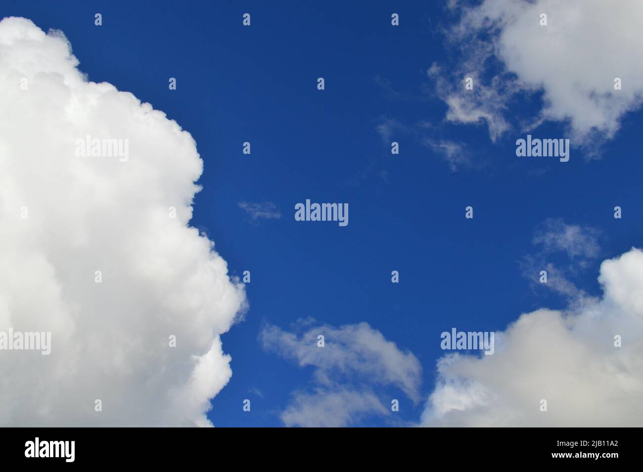 The sun shines through a blue sky with white clouds Stock Photo Alamy