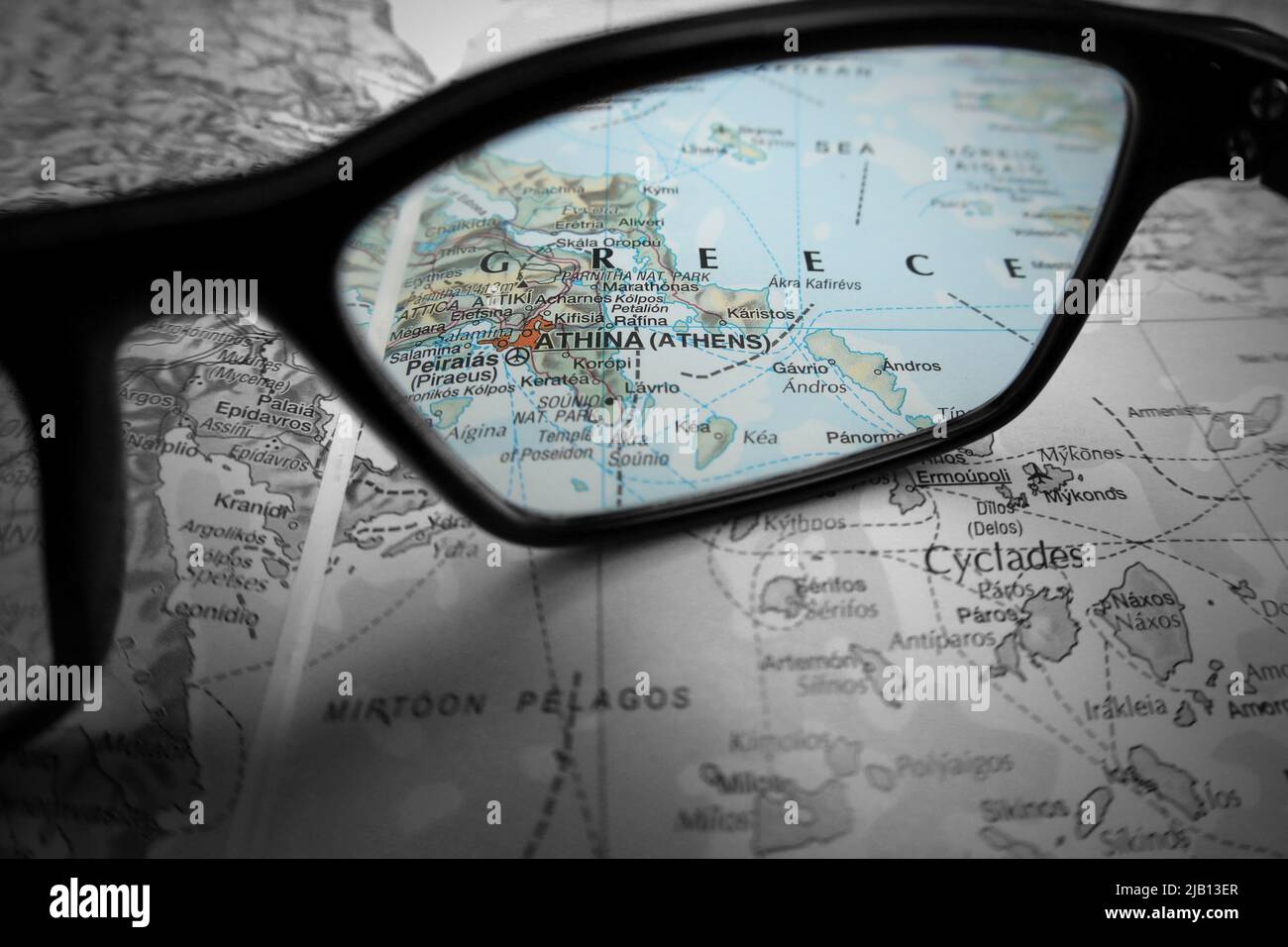 An creative illustrative image showing the country of Greece and city of Athens on a map through the lens of reading glasses. Stock Photo