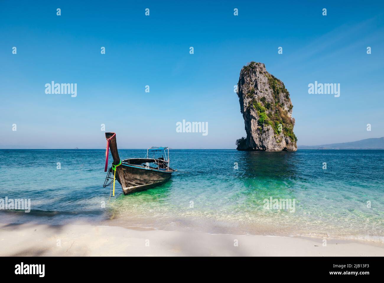 longtail boat anchored on a white sandy beach at Ko Poda Island during morning with tropical blue turquoise water and limestone rock in Krabi Thailand Stock Photo