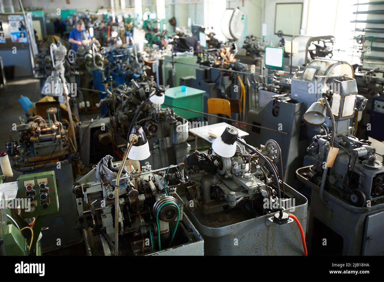 General view of clock factory shop full of machines with electric lamps