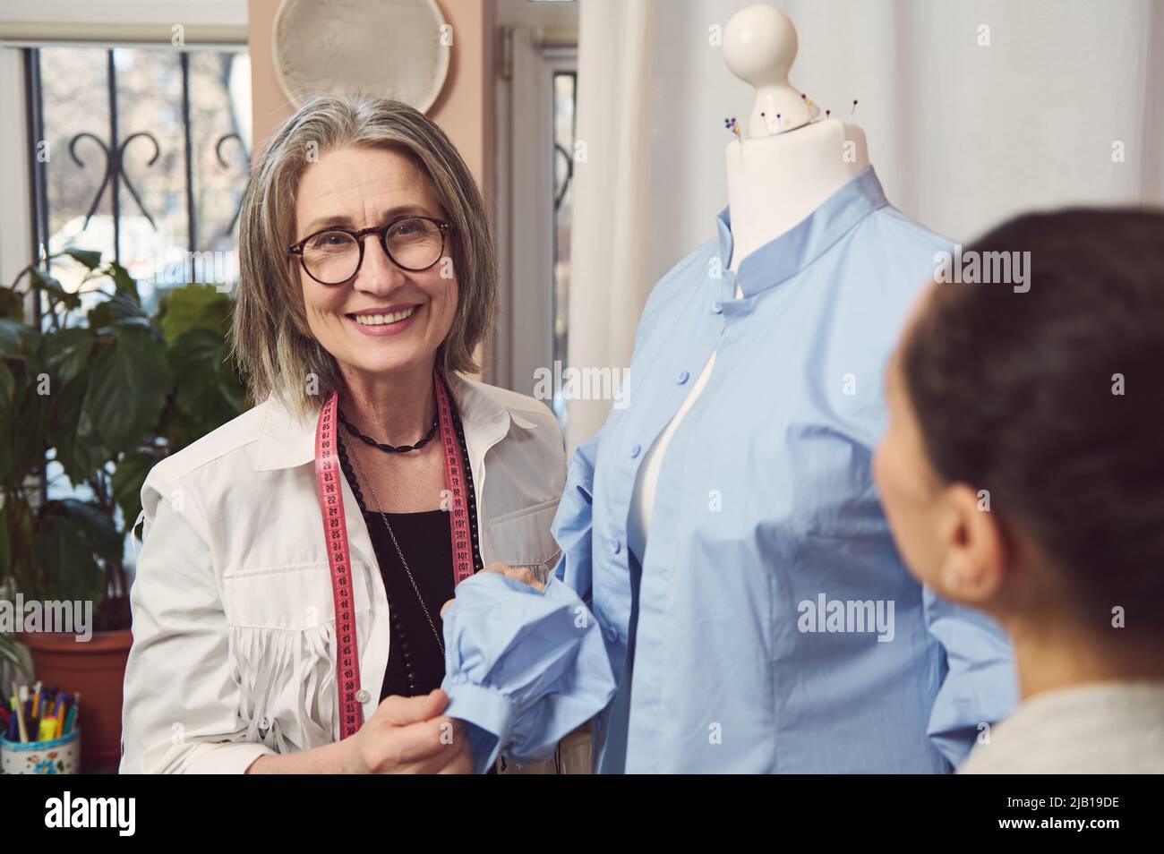 Smiling senior fashion designer try on a new dress shirt on a mannequin