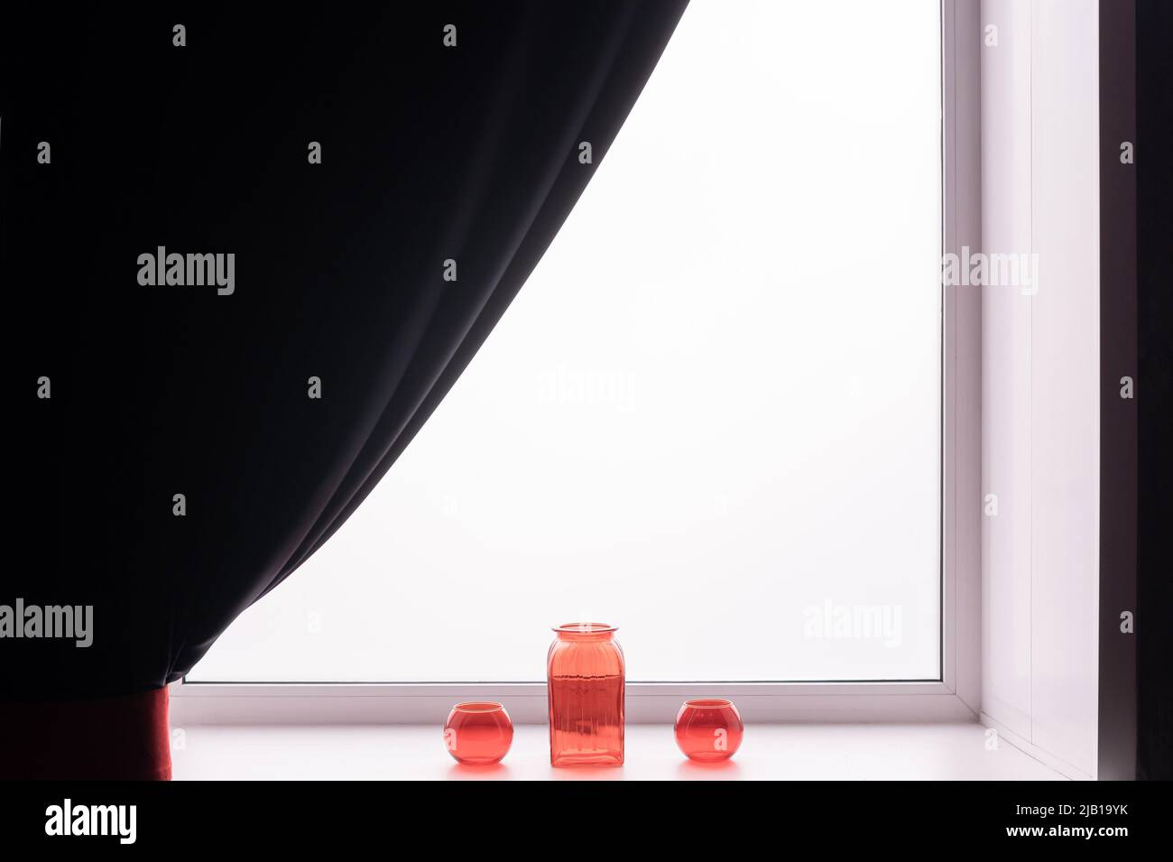 Three empty glass red vases on the windowsill. Stock Photo