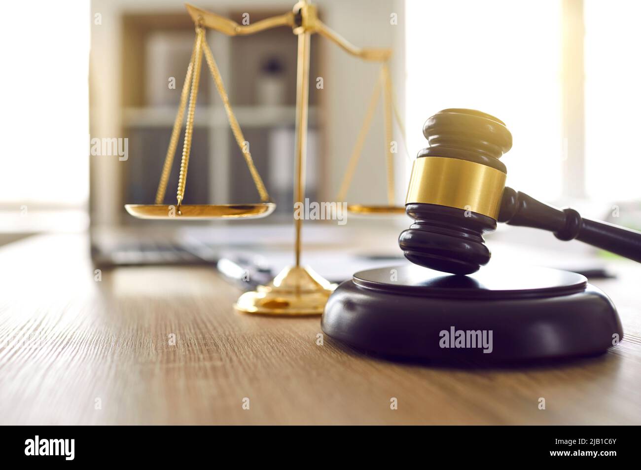Brown judge's gavel on sound block and scales of justice on table in