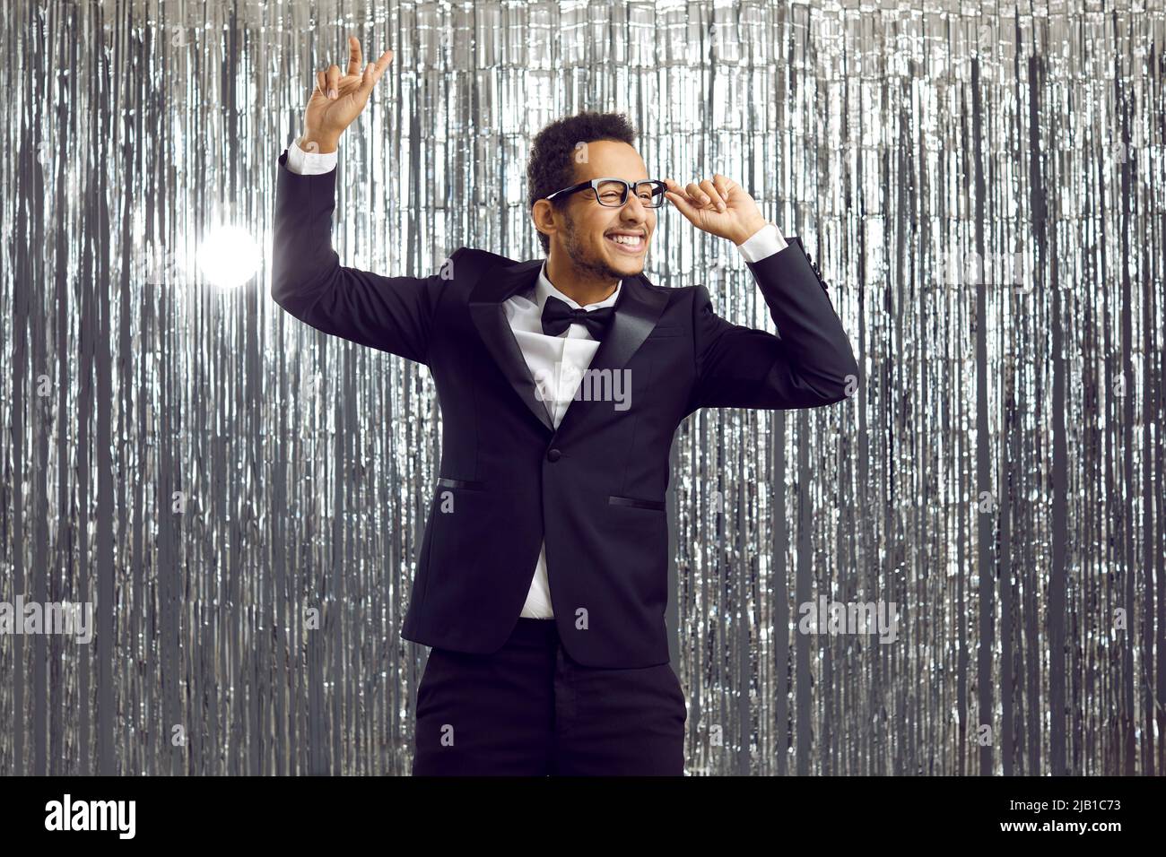 Happy funny young ethnic man in tuxedo suit dancing and having fun at disco party Stock Photo