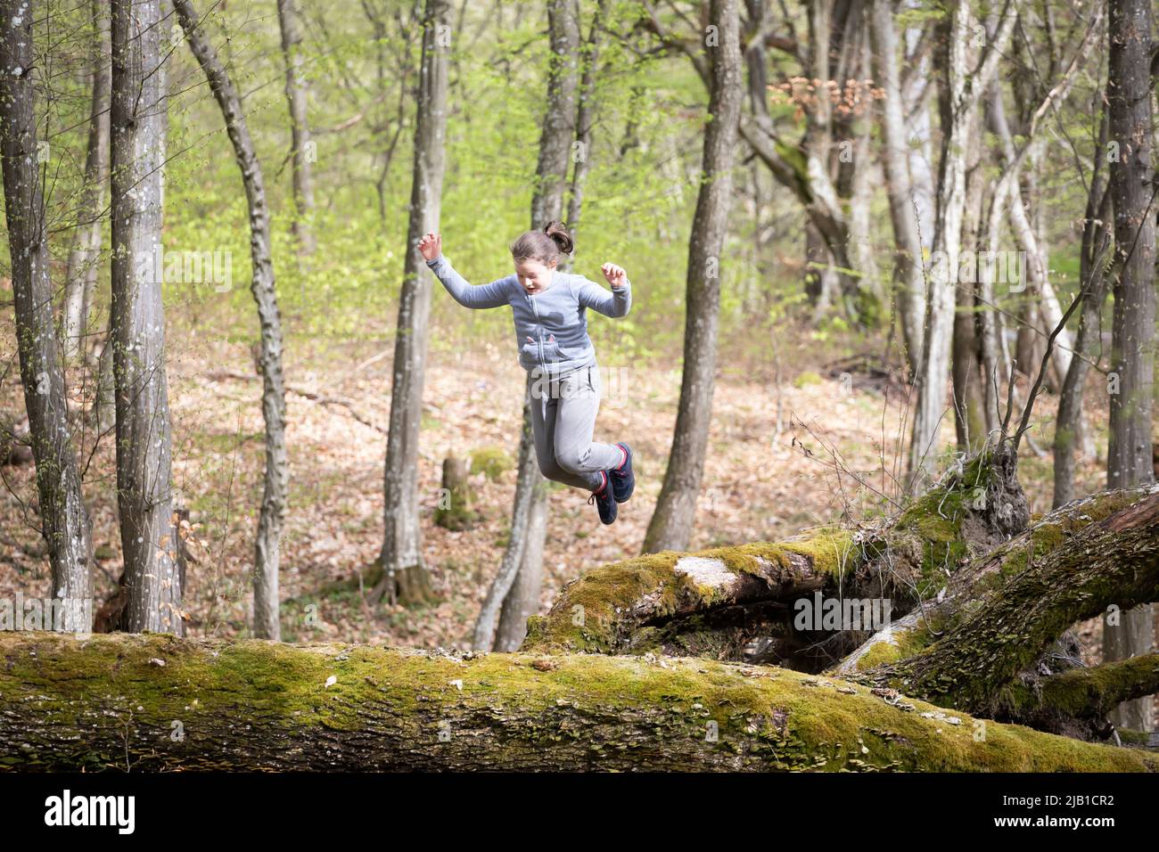 Little girl having fun, jumping in the forest. The concept of outdoor ...