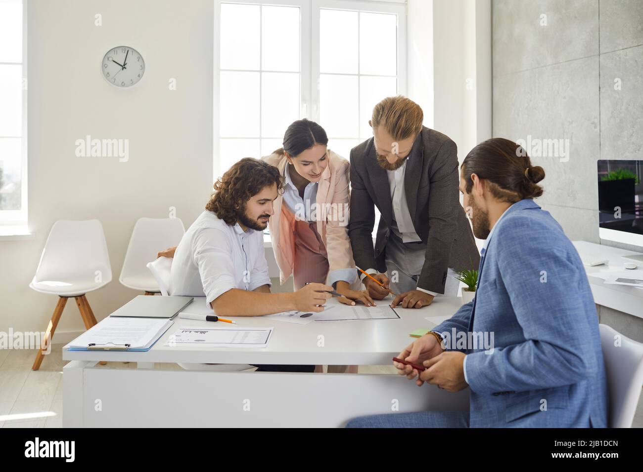 Colleagues in the office work together on a business project comparing data and analyzing lists. Stock Photo