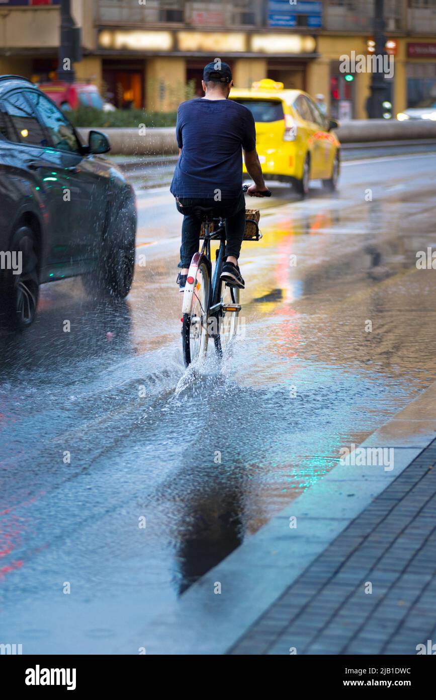 Man crossing a puddle on a bicycle with his with legs up Stock Photo