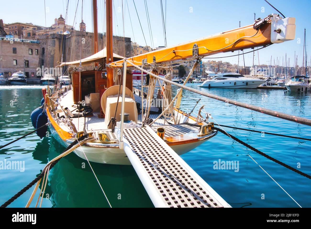 A luxury sailboat moored in a Mediterranean harbor with the gangplank extended Stock Photo