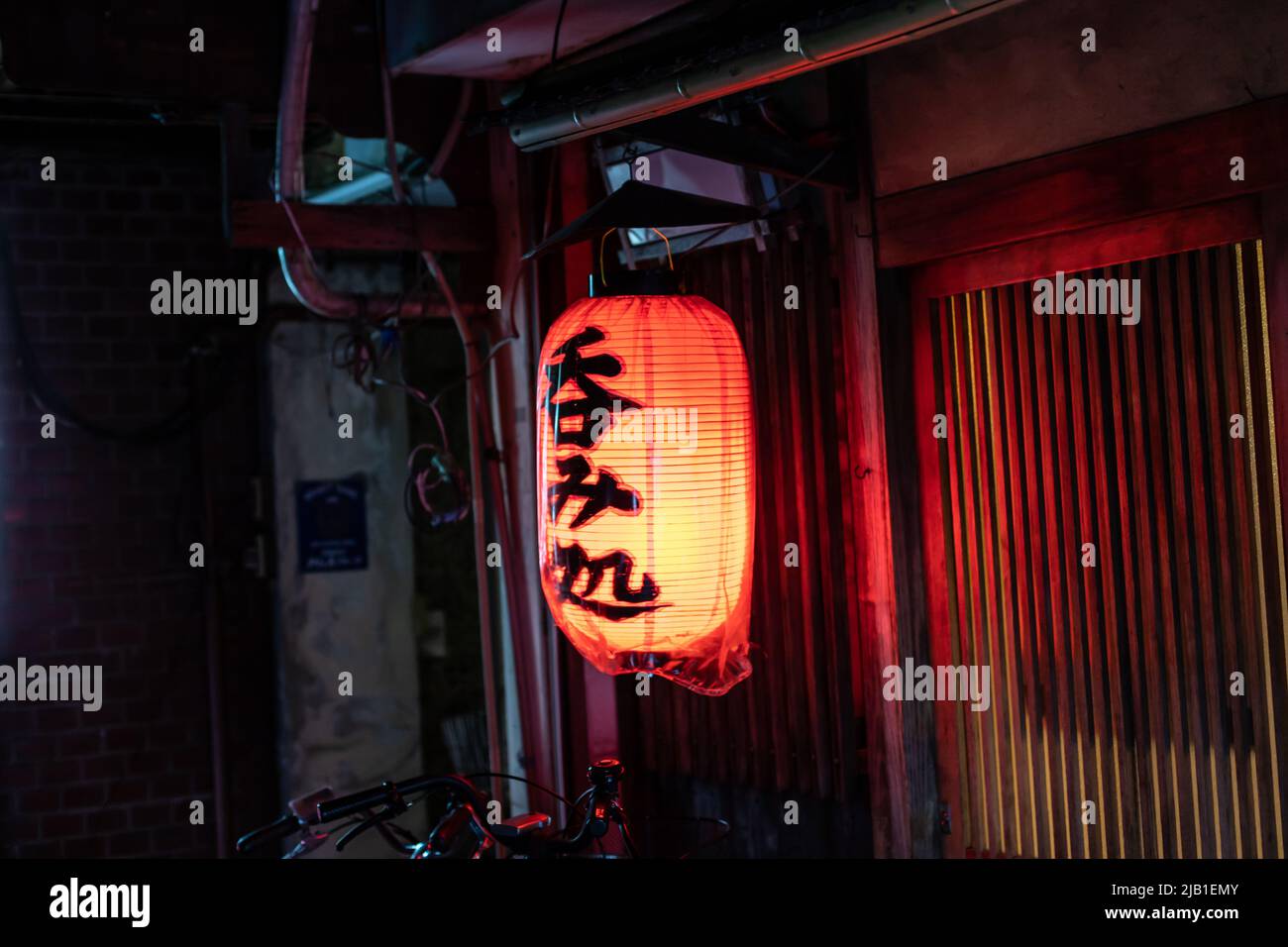 Close up Japanese paper lanterns at the wooden entrance of local Izakaya restaurant at night, Kyoto, Japan. Translation : The Place to Drink Stock Photo