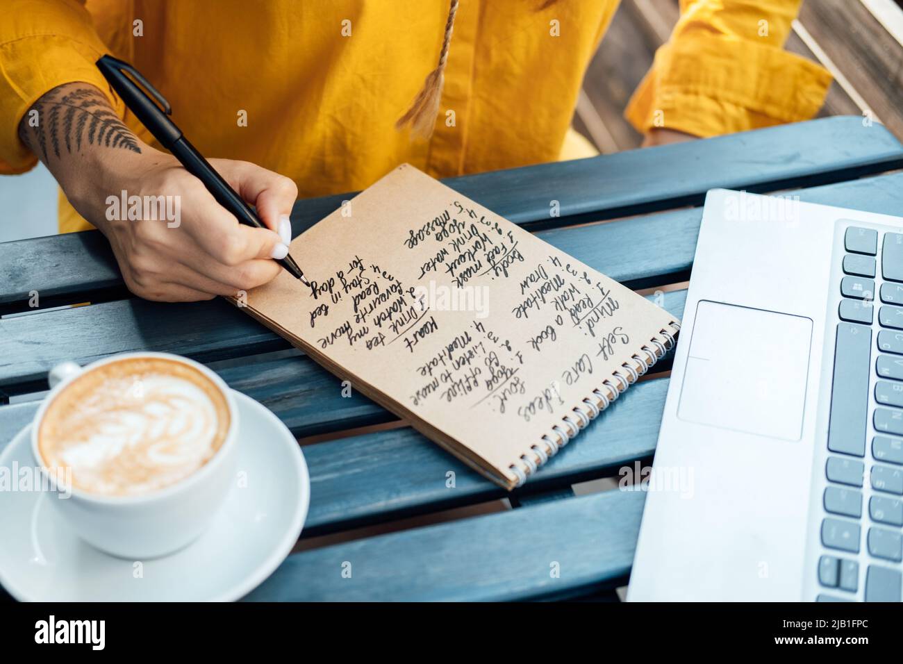 Young woman writing in notebook self-care ideas list for the mind, soul, body Stock Photo