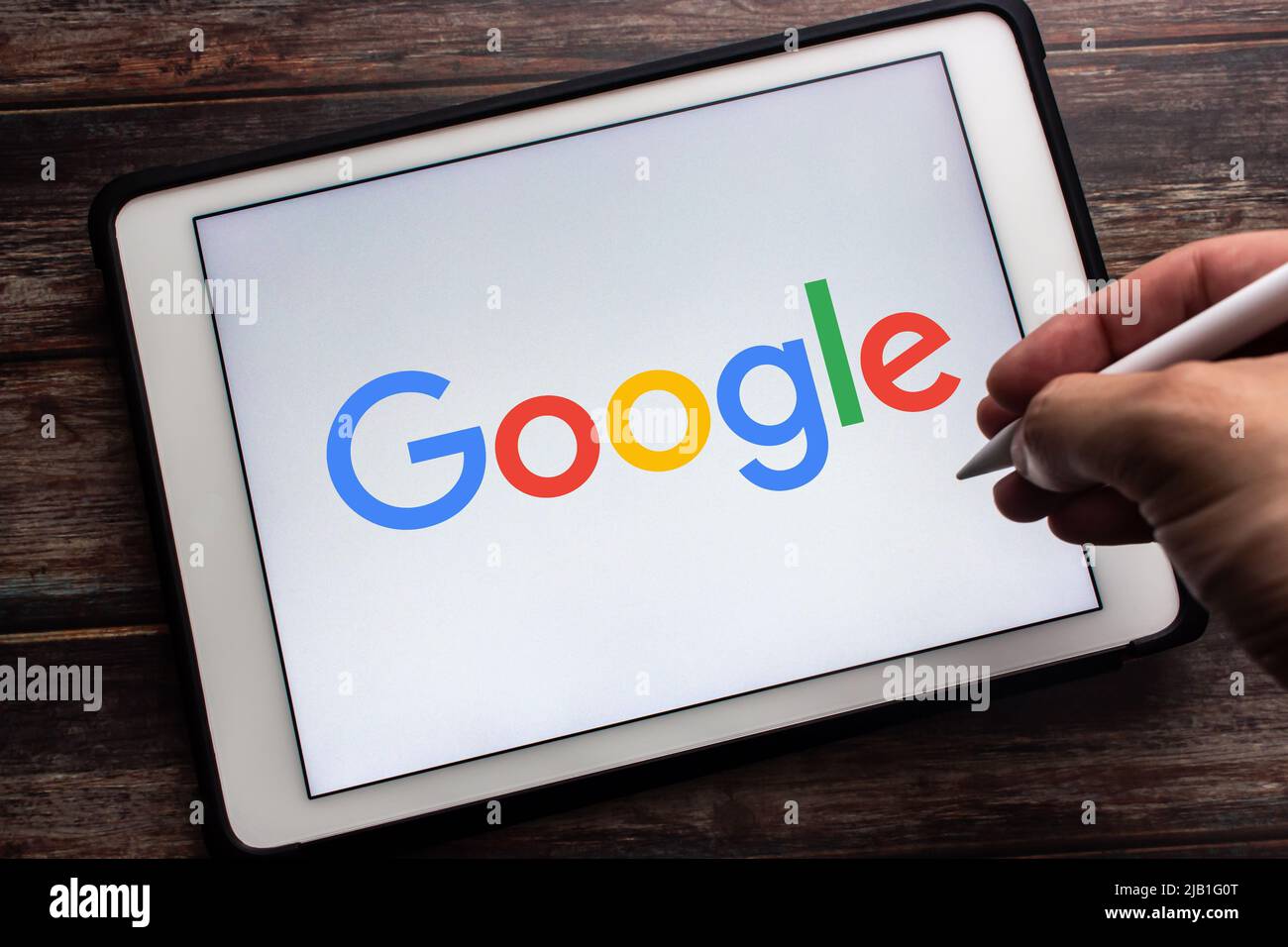 Closeup logo of Google on tablet. Man hand holding stylus pen. Google is US multinational company that specializes in Internet-related services Stock Photo
