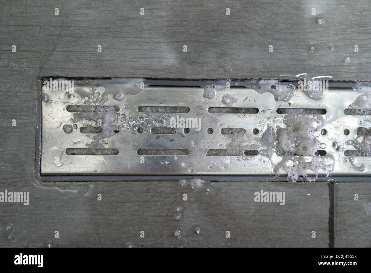 Drain hole with pipe cleaner in metal sink. Foam with bubbles of