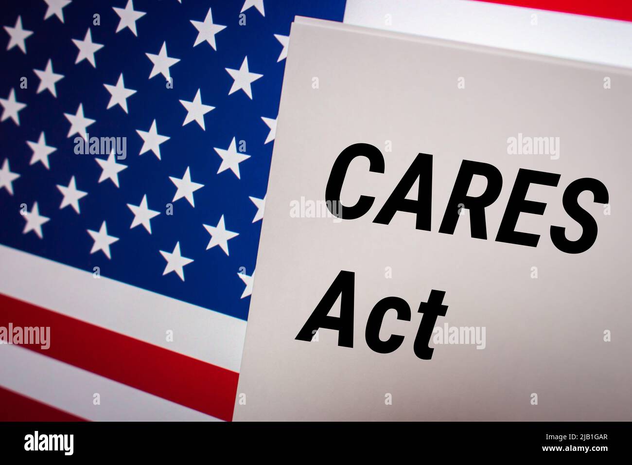 Conceptual keyword CARES Act (The Coronavirus Aid, Relief, and Economic Security Act) on card on US flag background. Business, economy, social concept Stock Photo