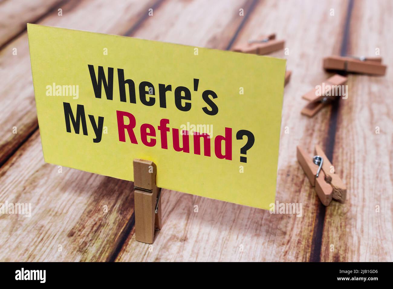 Message card “Where is My Refund?” on shabby wooden table. Natural wooden pinch holding yellow paper note. Concept of business, economy and finance Stock Photo