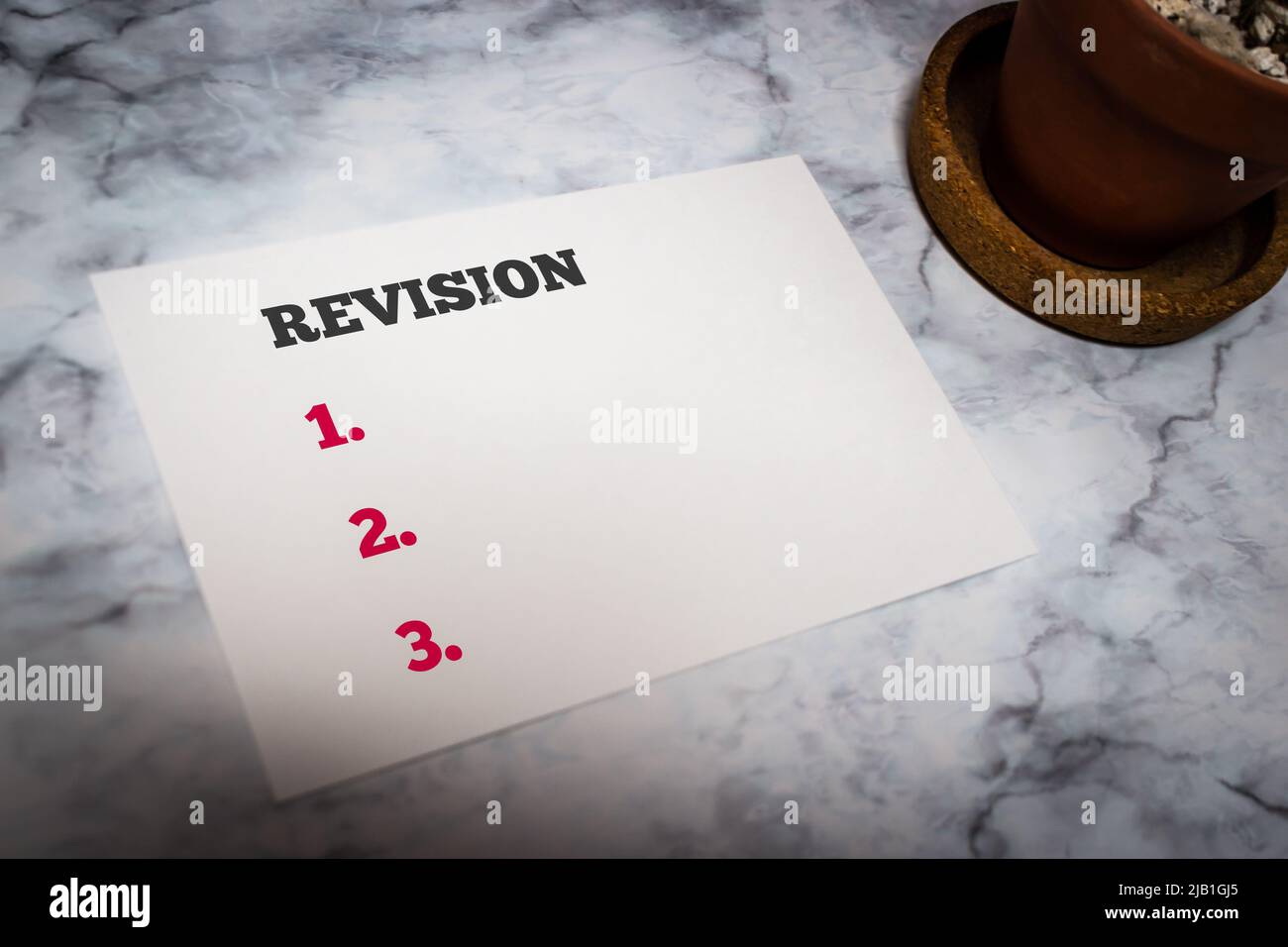 Message card showing Revision (with personal task list copy space) on white marble table with cactus. Action of setting personal goals or task concept Stock Photo