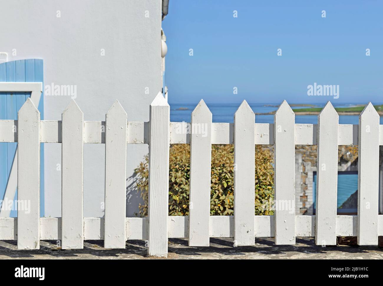 closeup on white fence of a hose in Brittany- France  in front of the seashore under blue sky Stock Photo